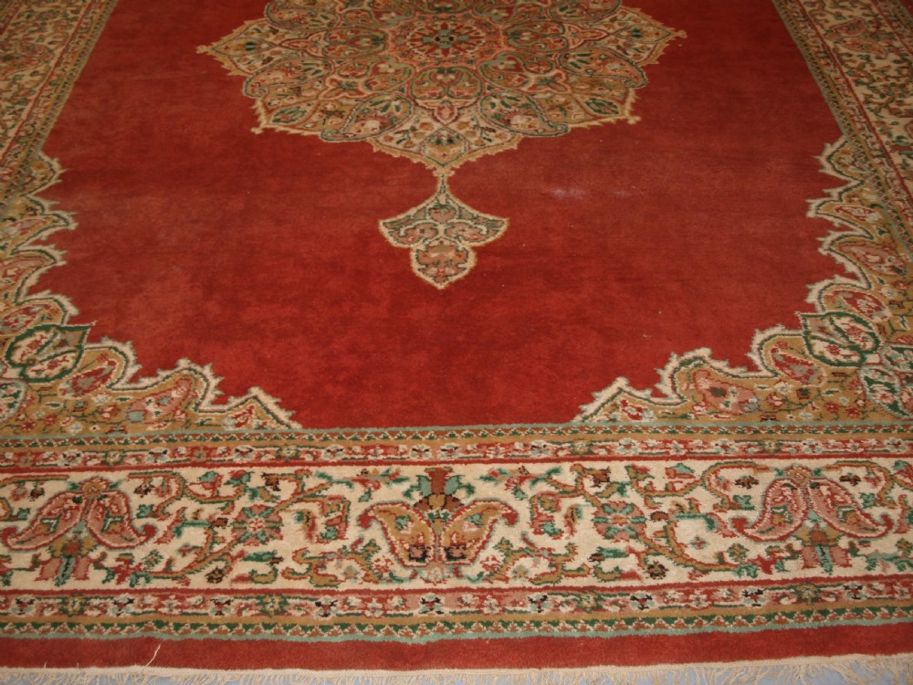 An antique Turkish Isparta wool carpet featuring a warm red field decorated with a central floral medallion and pastel borders. View VII