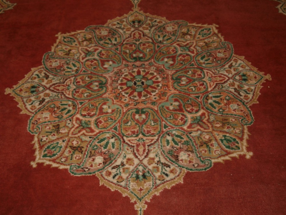 An antique Turkish Isparta wool carpet featuring a warm red field decorated with a central floral medallion and pastel borders. View X