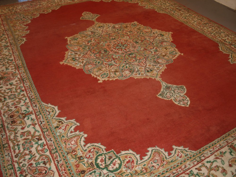 An antique Turkish Isparta wool carpet featuring a warm red field decorated with a central floral medallion and pastel borders. View XII