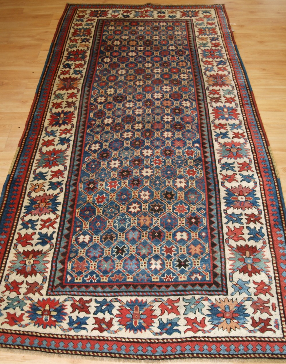 ANTIQUE CAUCASIAN GENDJE KAZAK RUG, LATTICE AND STAR DESIGN, CIRCA 1880.