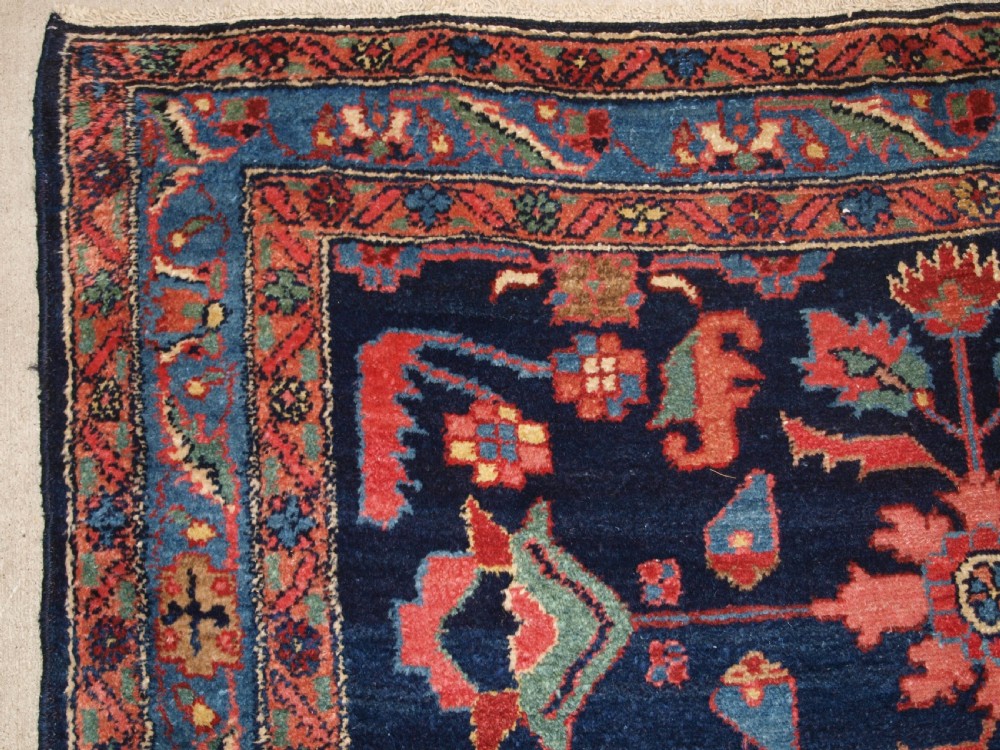 An antique Persian Hamadan wool runner featuring geometric floral patterns in red, green, and blue on a dark navy field surrounded by ornate multi-band borders. View III