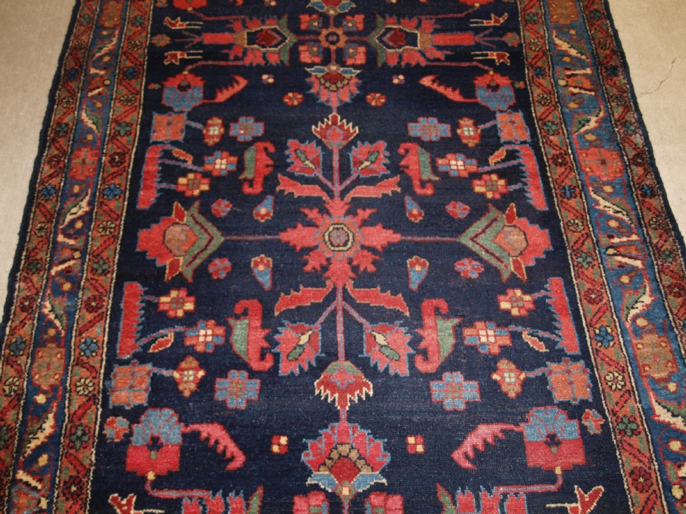 An antique Persian Hamadan wool runner featuring geometric floral patterns in red, green, and blue on a dark navy field surrounded by ornate multi-band borders. View V