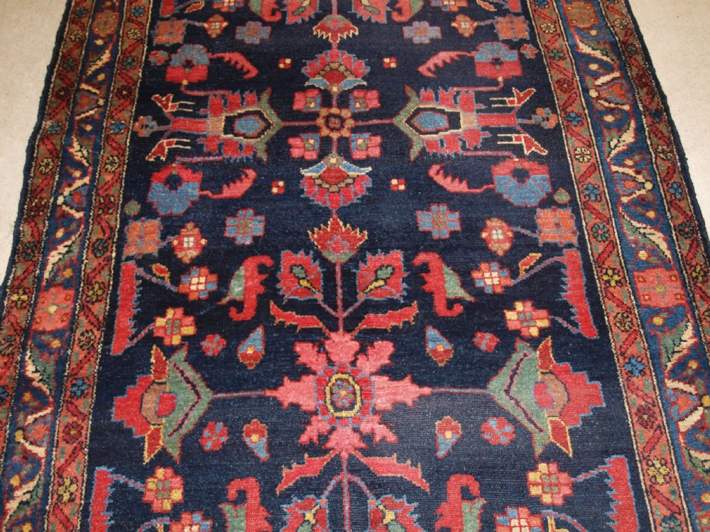 An antique Persian Hamadan wool runner featuring geometric floral patterns in red, green, and blue on a dark navy field surrounded by ornate multi-band borders. View VI