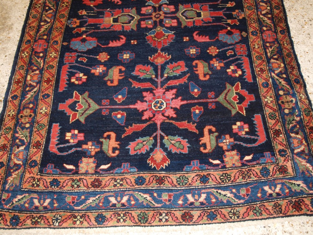 An antique Persian Hamadan wool runner featuring geometric floral patterns in red, green, and blue on a dark navy field surrounded by ornate multi-band borders. View IX
