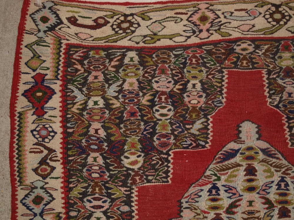 An antique Persian Senneh kilim runner featuring a sequence of linked diamond medallions on a vibrant red field with intricate geometric borders. View VII