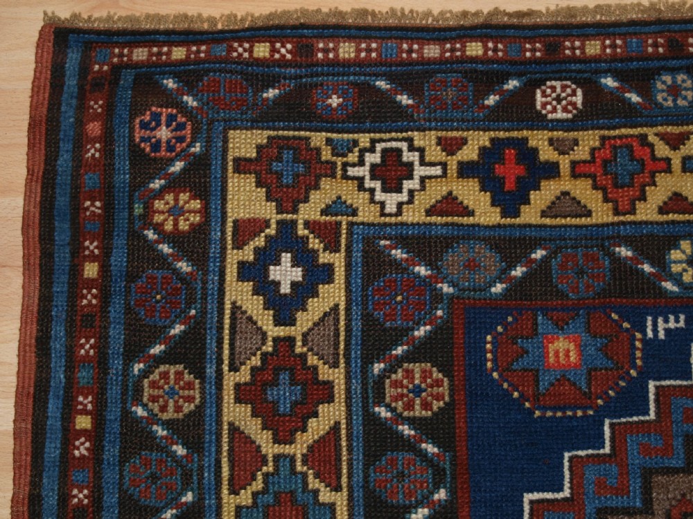 An antique Caucasian Kazak long rug featuring five stepped diamond medallions along a rich indigo blue field, framed by decorative geometric borders. View II