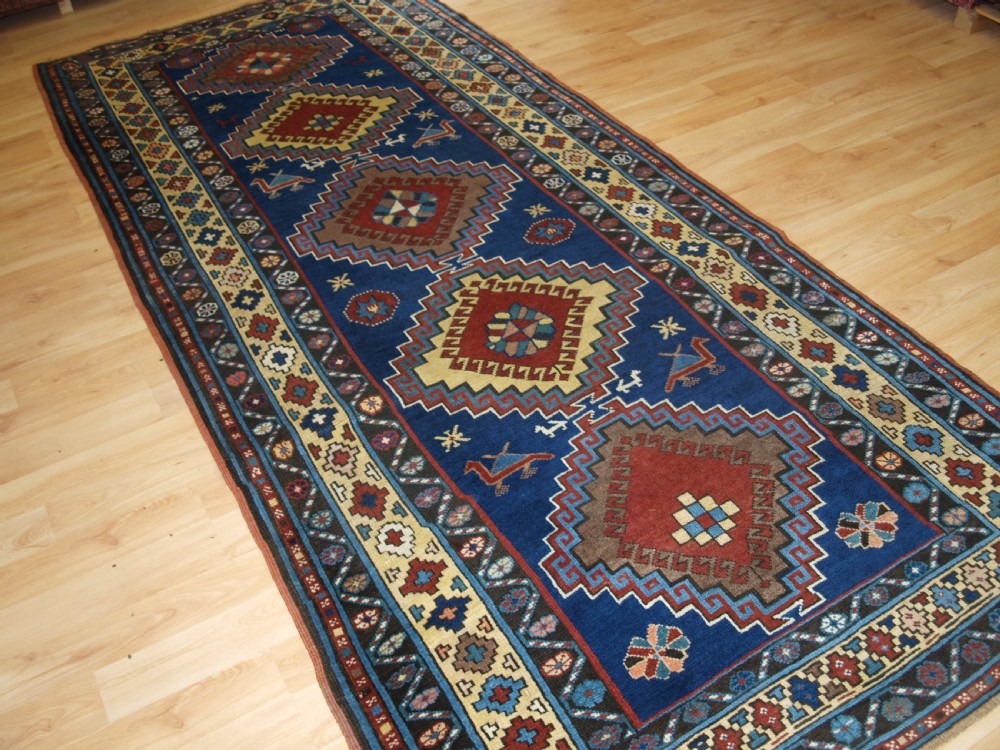 An antique Caucasian Kazak long rug featuring five stepped diamond medallions along a rich indigo blue field, framed by decorative geometric borders. View III