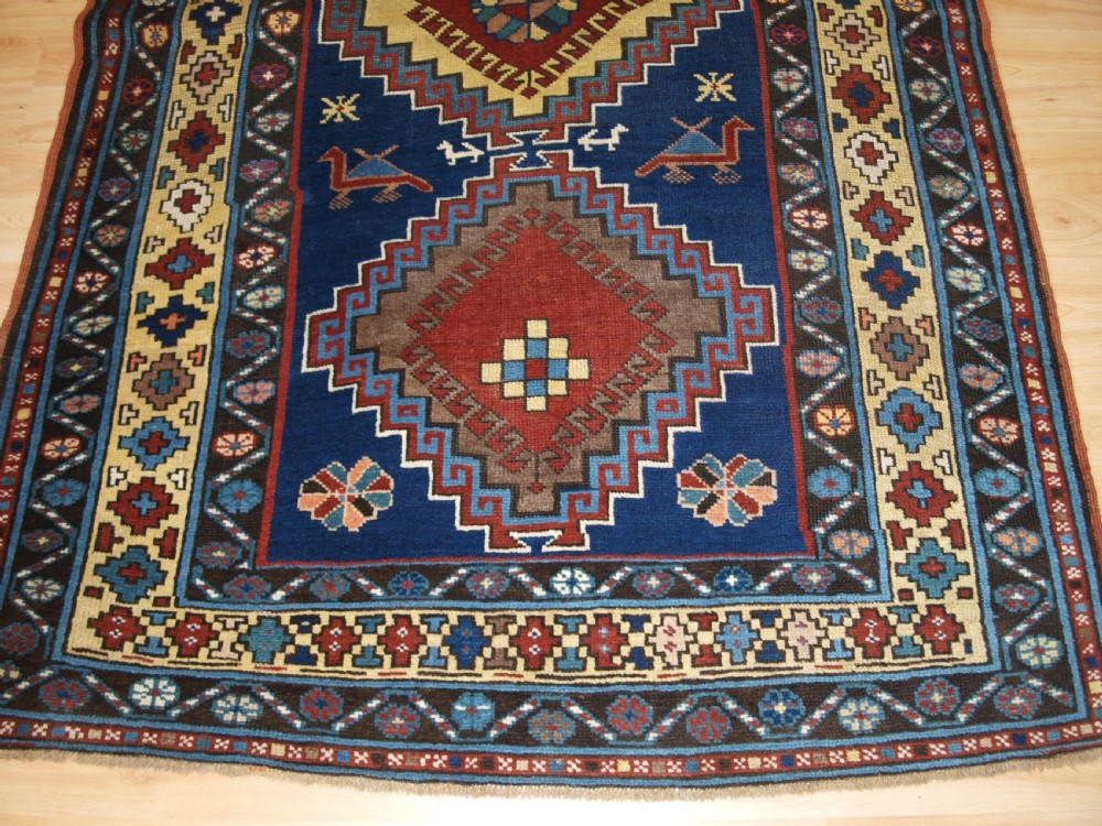 An antique Caucasian Kazak long rug featuring five stepped diamond medallions along a rich indigo blue field, framed by decorative geometric borders. View VII