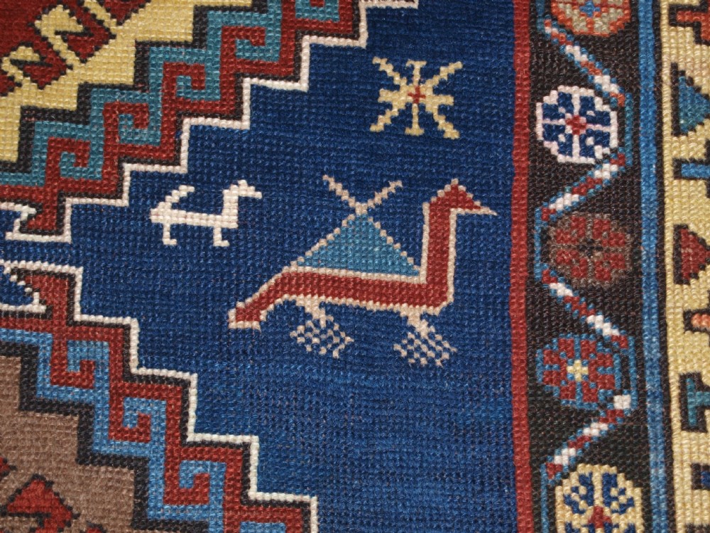 An antique Caucasian Kazak long rug featuring five stepped diamond medallions along a rich indigo blue field, framed by decorative geometric borders. View VIII