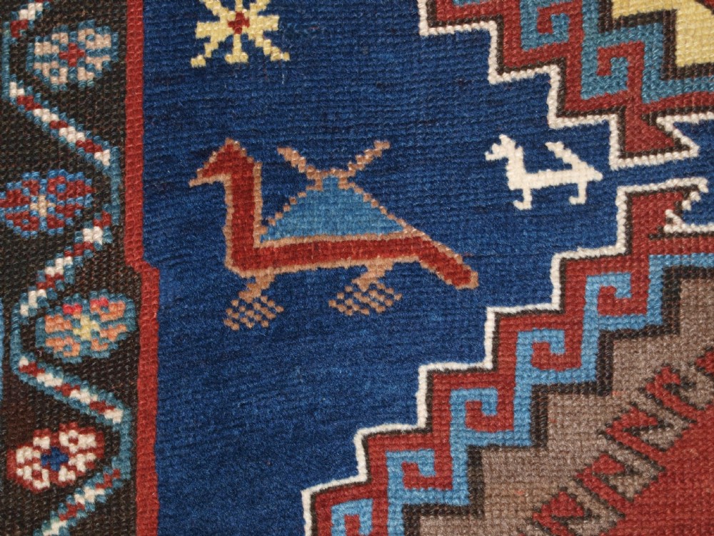 An antique Caucasian Kazak long rug featuring five stepped diamond medallions along a rich indigo blue field, framed by decorative geometric borders. View IX