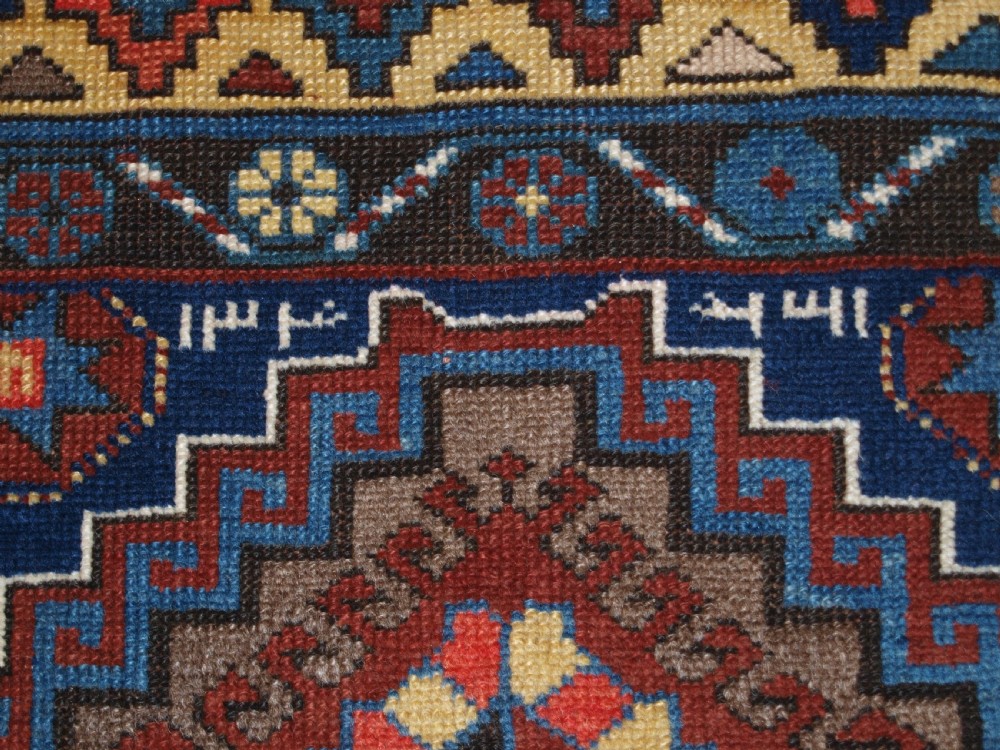 An antique Caucasian Kazak long rug featuring five stepped diamond medallions along a rich indigo blue field, framed by decorative geometric borders. View XI