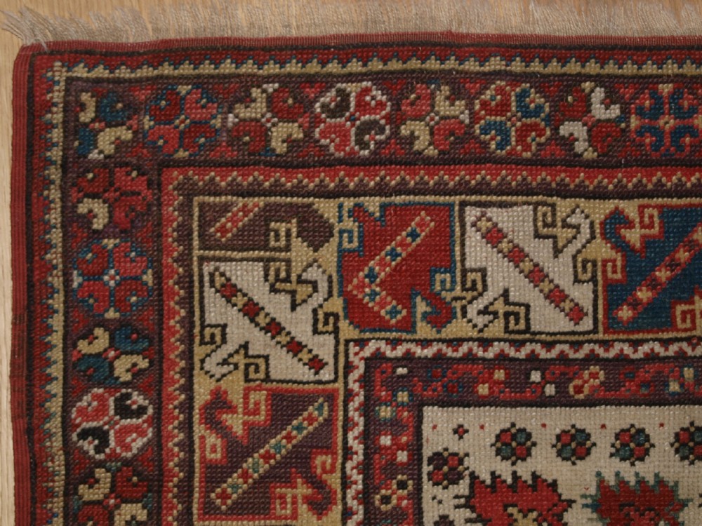 A late 19th-century Anatolian wool rug featuring a terracotta red geometric stepped mihrab niche framed by patterned multi-tiered borders in cream, blue, and red. View II