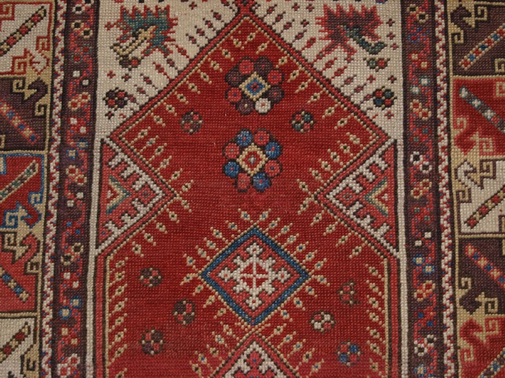 A late 19th-century Anatolian wool rug featuring a terracotta red geometric stepped mihrab niche framed by patterned multi-tiered borders in cream, blue, and red. View VII