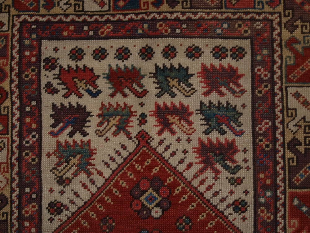 A late 19th-century Anatolian wool rug featuring a terracotta red geometric stepped mihrab niche framed by patterned multi-tiered borders in cream, blue, and red. View VIII