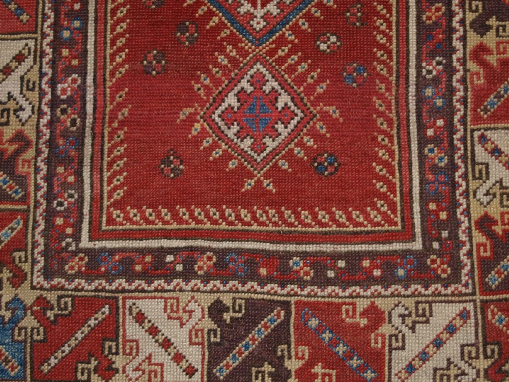 A late 19th-century Anatolian wool rug featuring a terracotta red geometric stepped mihrab niche framed by patterned multi-tiered borders in cream, blue, and red. View IX