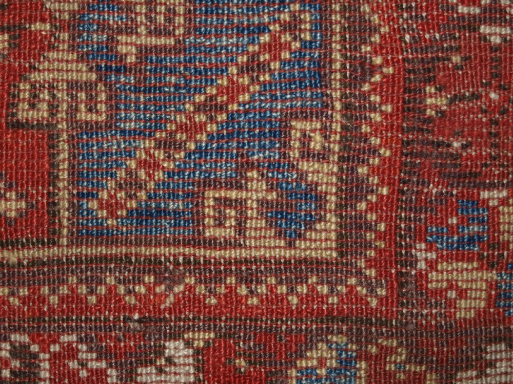 A late 19th-century Anatolian wool rug featuring a terracotta red geometric stepped mihrab niche framed by patterned multi-tiered borders in cream, blue, and red. View XII