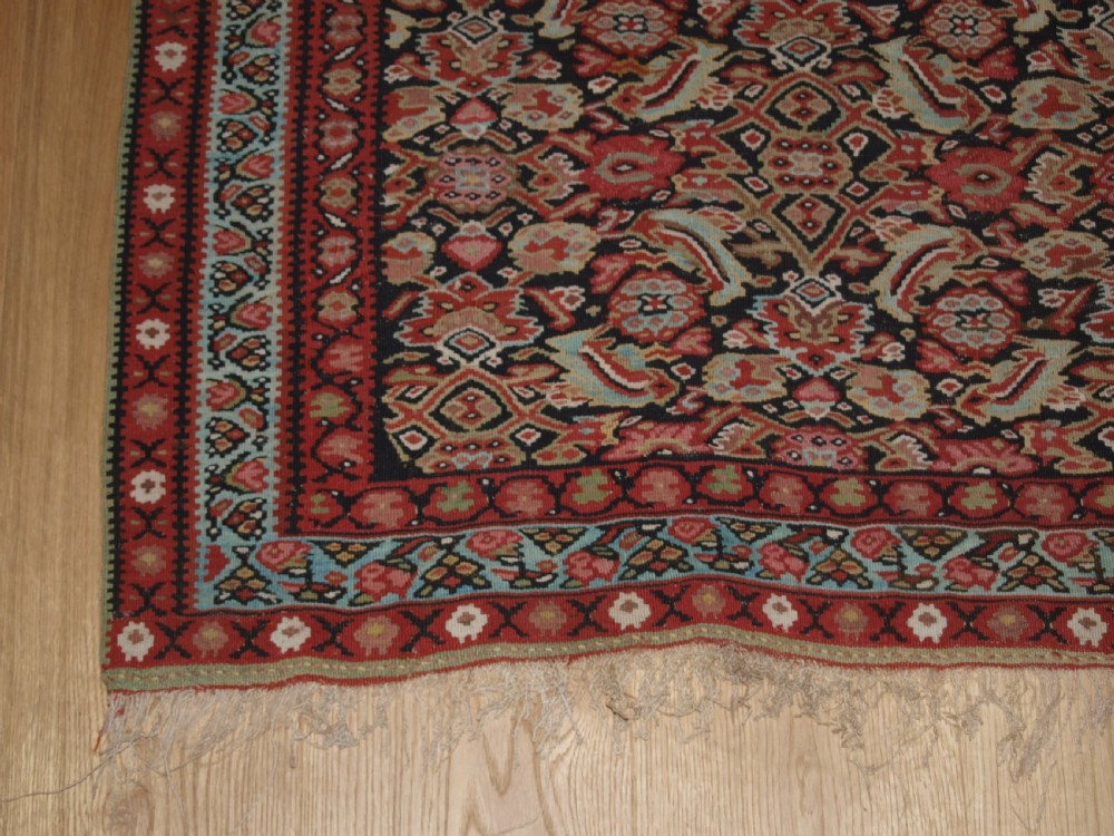 An antique flatwoven Persian Senneh kilim rug featuring a detailed central rectangle and surrounding border filled with intricate geometric and floral Herati patterns in red, ivory, and dark tones. View V