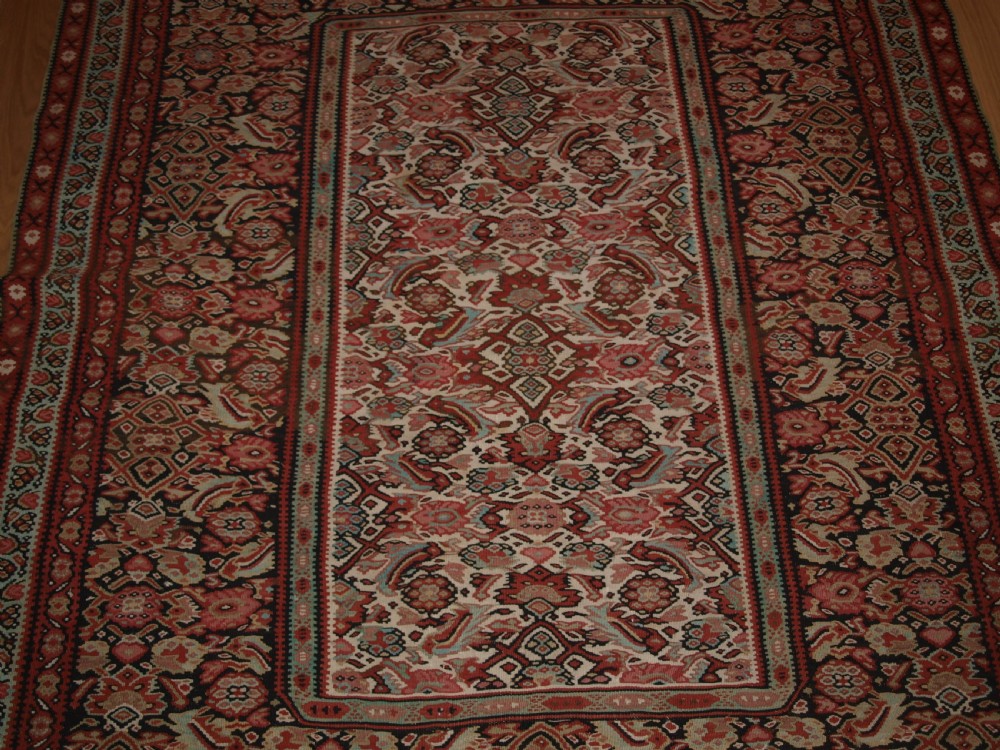 An antique flatwoven Persian Senneh kilim rug featuring a detailed central rectangle and surrounding border filled with intricate geometric and floral Herati patterns in red, ivory, and dark tones. View VIII