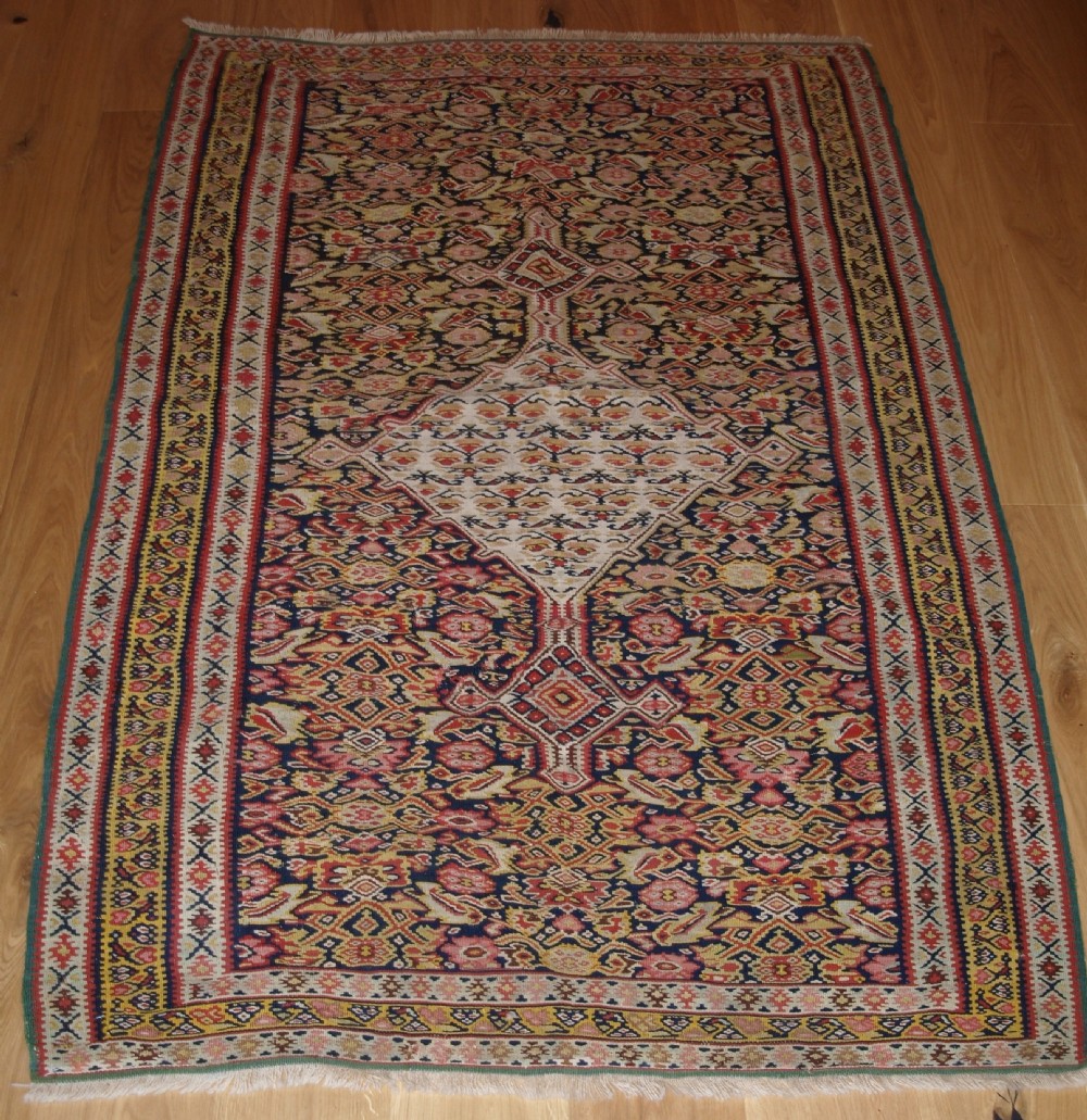 ANTIQUE SENNEH KILIM WITH MEDALLION DESIGN, SOFT COLOURS, CIRCA 1900.