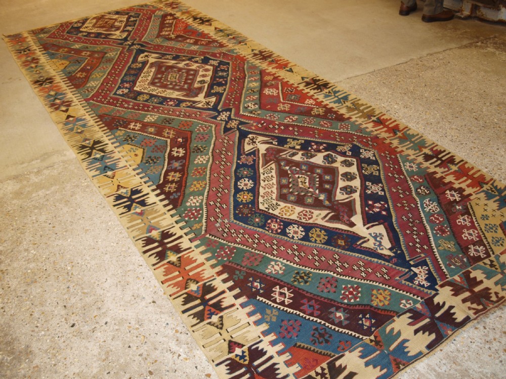 A large flatwoven late 19th-century Turkish Malatya kilim rug with central geometric diamond medallions in red, blue, green, and cream wool.