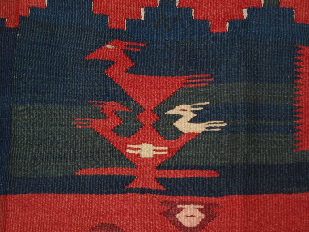 A large flatwoven Balkan Sharkoy kilim rug featuring terracotta red and navy blue borders decorated with stylised bird motifs and geometric patterns. View VIII