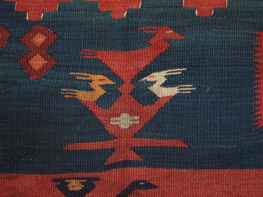 A large flatwoven Balkan Sharkoy kilim rug featuring terracotta red and navy blue borders decorated with stylised bird motifs and geometric patterns. View IX