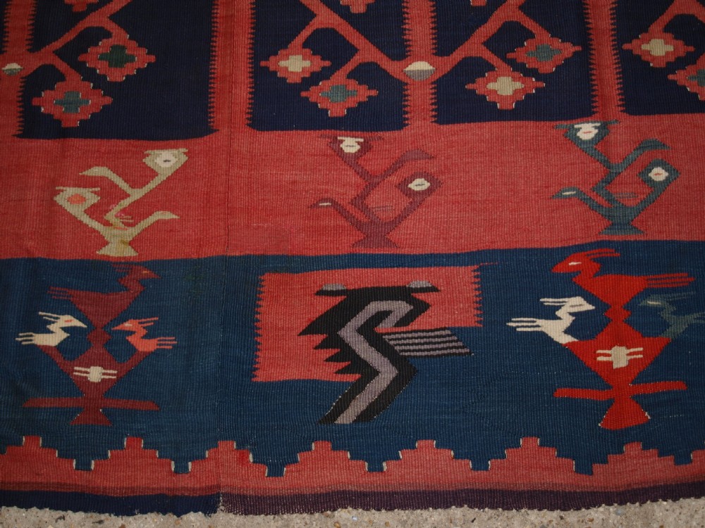 A large flatwoven Balkan Sharkoy kilim rug featuring terracotta red and navy blue borders decorated with stylised bird motifs and geometric patterns. View XVI