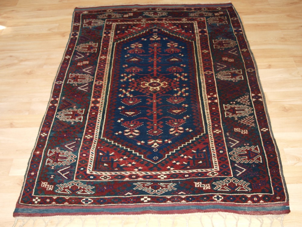 A hand-knotted Turkish Dosemealti wool rug featuring a navy blue geometric central field surrounded by deep red patterned borders.
