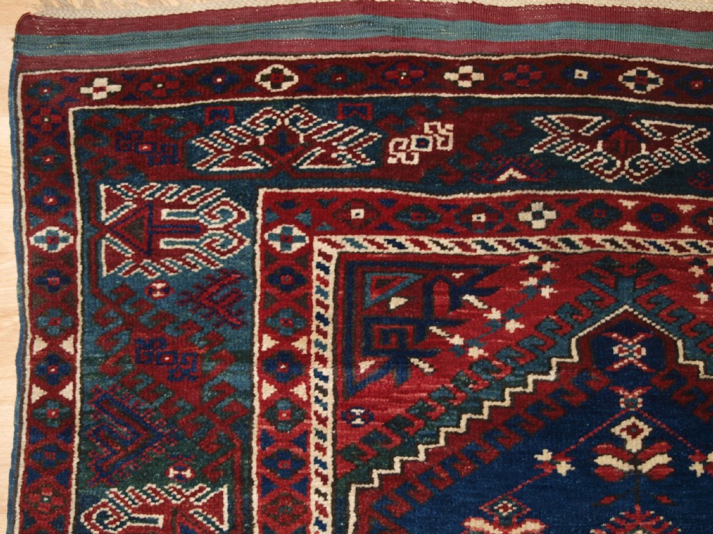A hand-knotted Turkish Dosemealti wool rug featuring a navy blue geometric central field surrounded by deep red patterned borders. View III