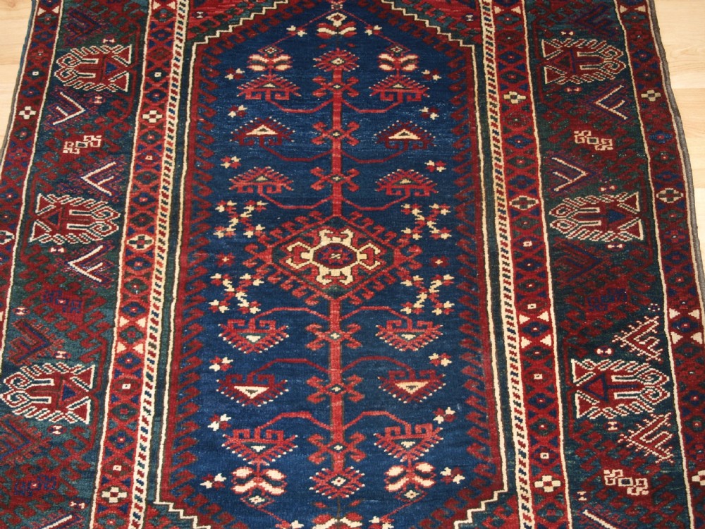 A hand-knotted Turkish Dosemealti wool rug featuring a navy blue geometric central field surrounded by deep red patterned borders. View V