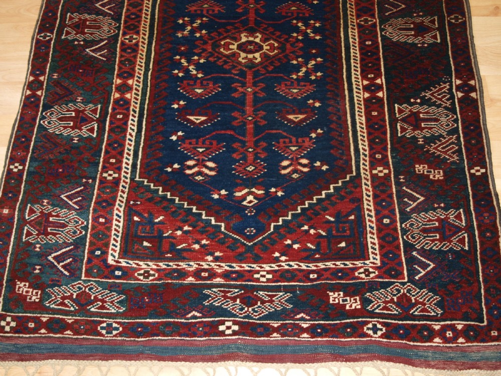 A hand-knotted Turkish Dosemealti wool rug featuring a navy blue geometric central field surrounded by deep red patterned borders. View VI