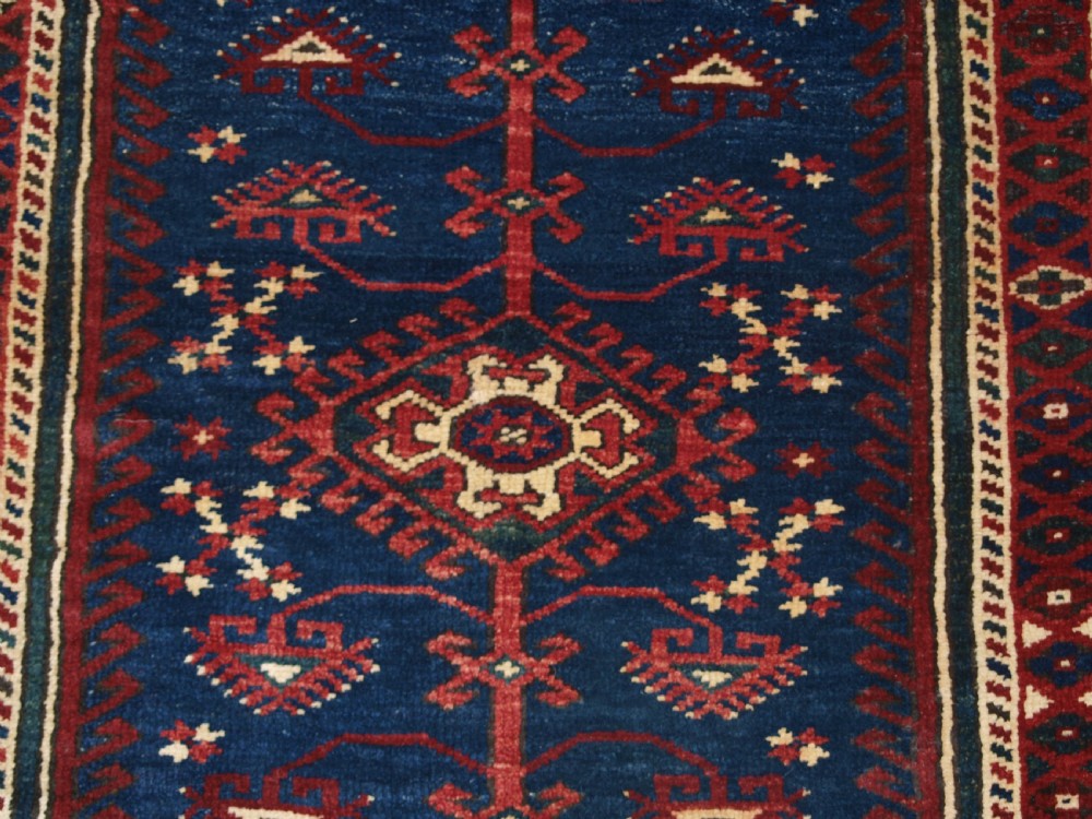 A hand-knotted Turkish Dosemealti wool rug featuring a navy blue geometric central field surrounded by deep red patterned borders. View VIII