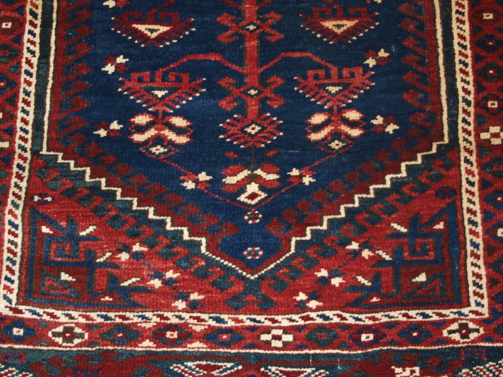 A hand-knotted Turkish Dosemealti wool rug featuring a navy blue geometric central field surrounded by deep red patterned borders. View IX