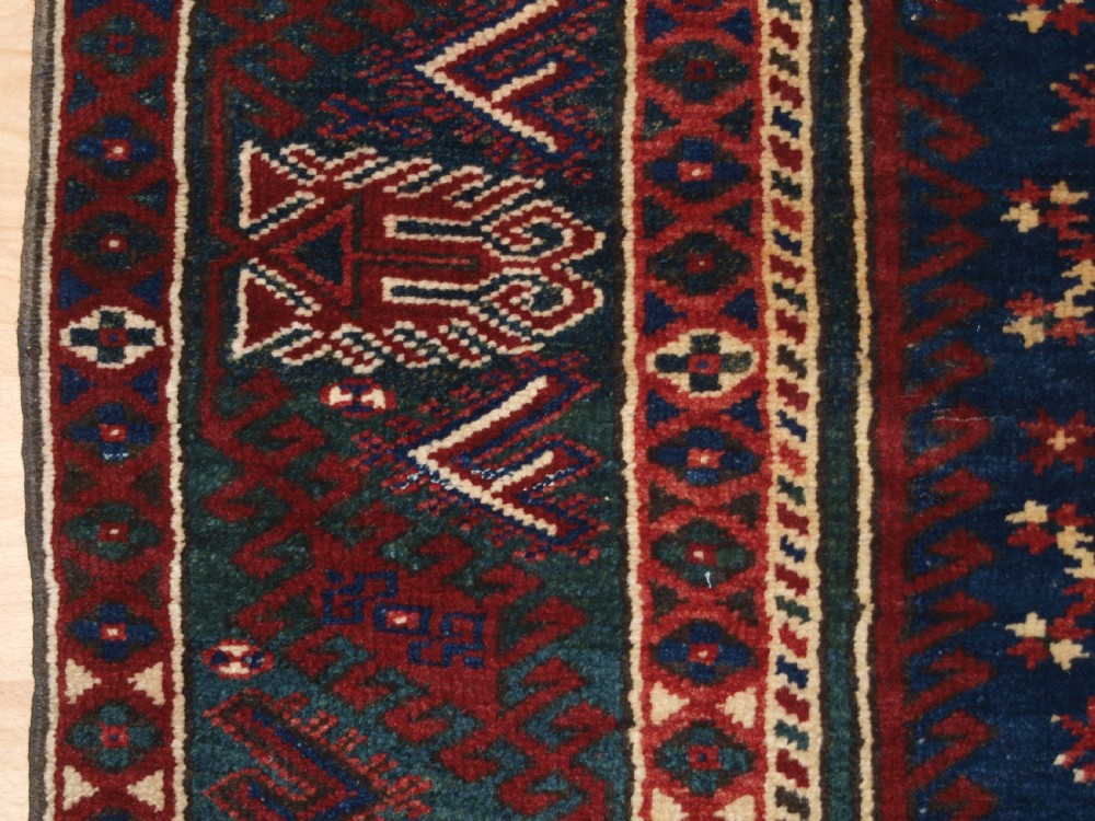 A hand-knotted Turkish Dosemealti wool rug featuring a navy blue geometric central field surrounded by deep red patterned borders. View X