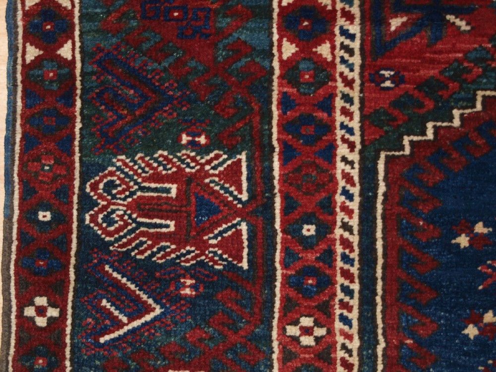 A hand-knotted Turkish Dosemealti wool rug featuring a navy blue geometric central field surrounded by deep red patterned borders. View XI
