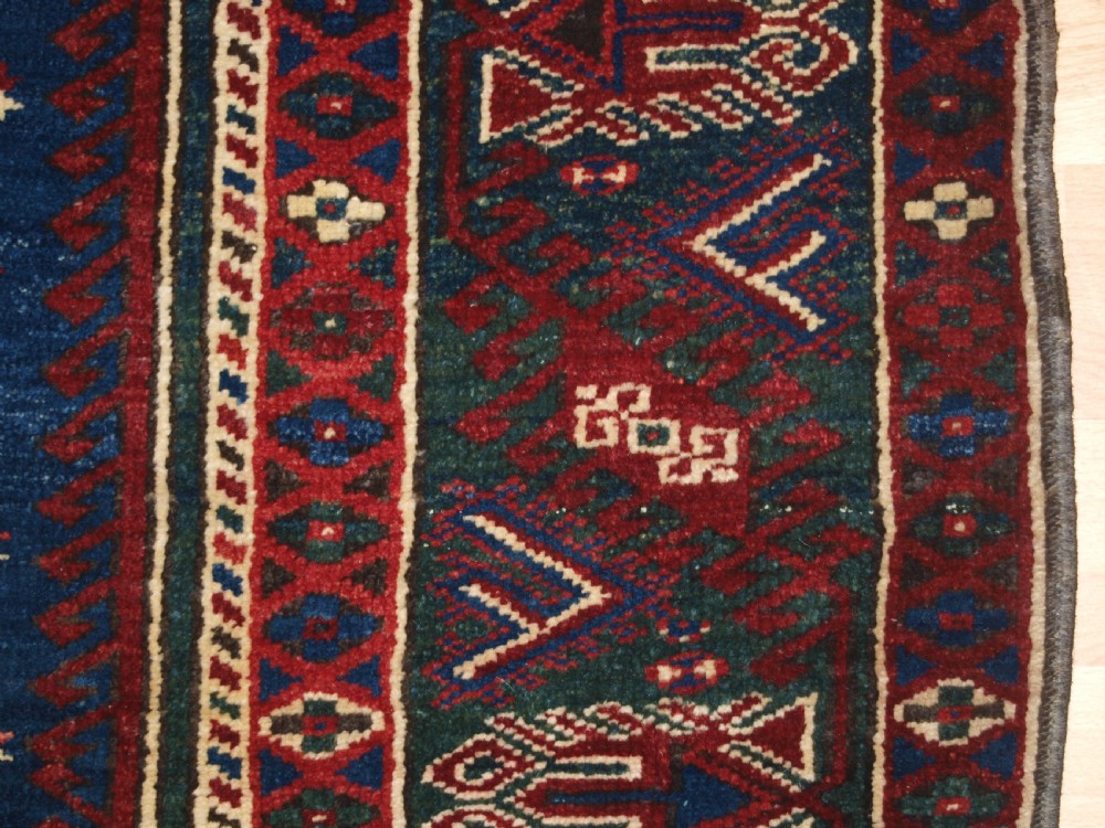 A hand-knotted Turkish Dosemealti wool rug featuring a navy blue geometric central field surrounded by deep red patterned borders. View XII