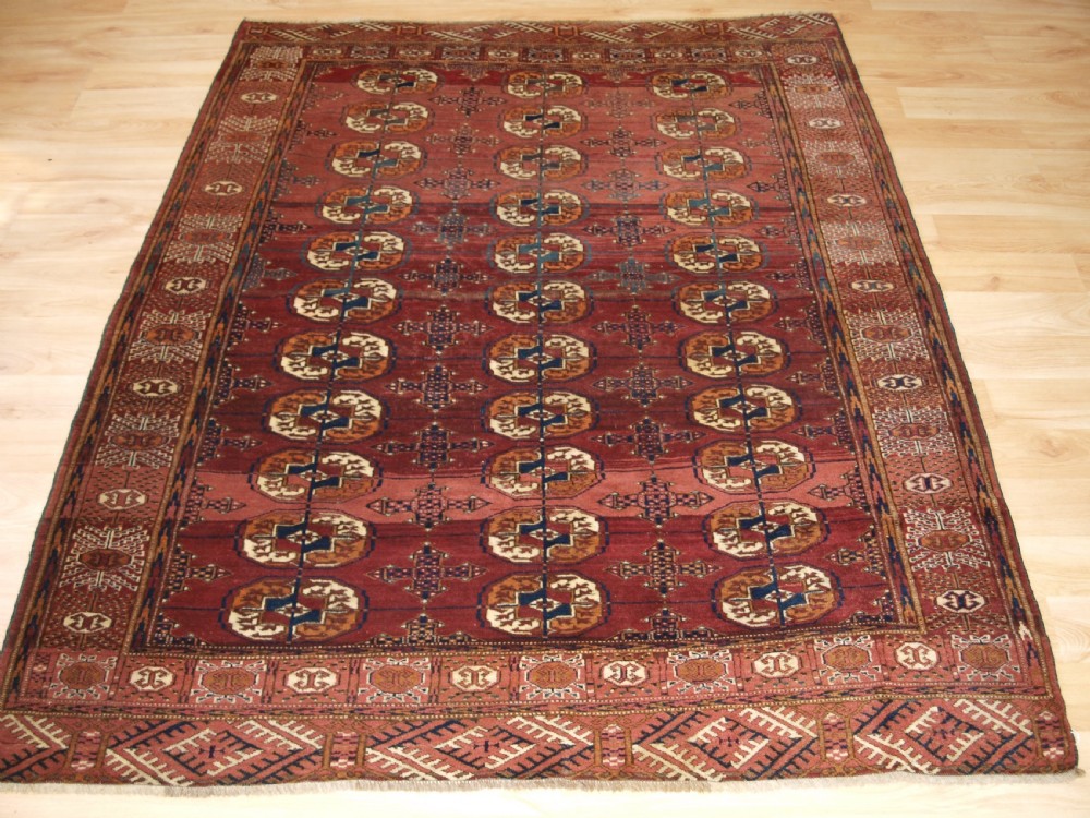 ANTIQUE TEKKE TURKMEN RUG WITH ABRASHED MADDER RED FIELD, CIRCA 1900.