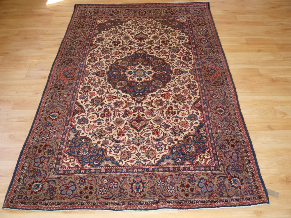 A rectangular hand-knotted Persian Tabriz wool rug with a central dark navy floral medallion on a cream field framed by multi-stripe borders.