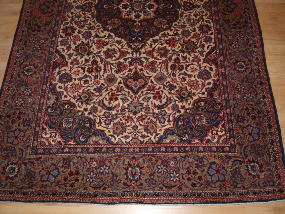 A rectangular hand-knotted Persian Tabriz wool rug with a central dark navy floral medallion on a cream field framed by multi-stripe borders. View V