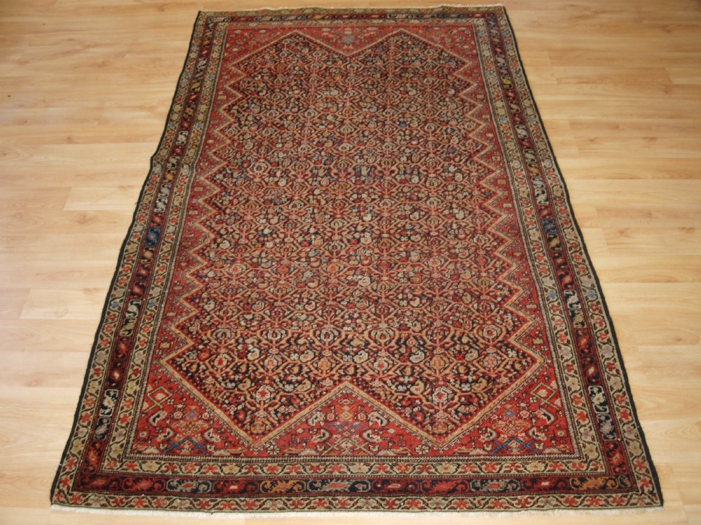 An antique hand-knotted Persian Malayer wool rug featuring an intricate red lattice pattern framed by multi-band decorative borders.