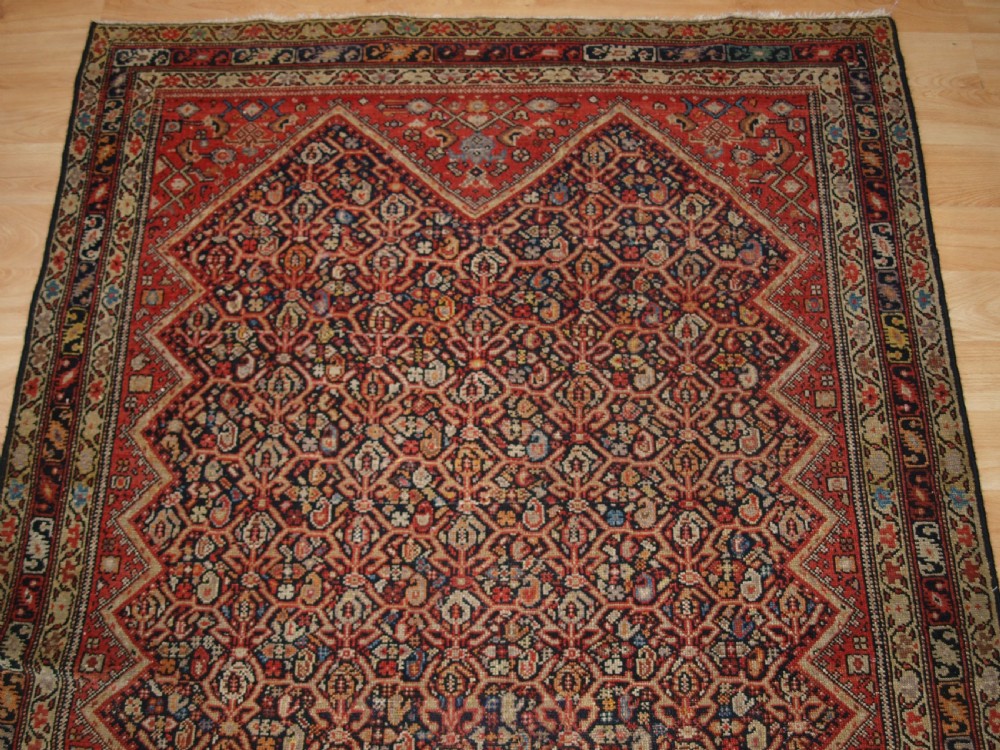 An antique hand-knotted Persian Malayer wool rug featuring an intricate red lattice pattern framed by multi-band decorative borders. View IV