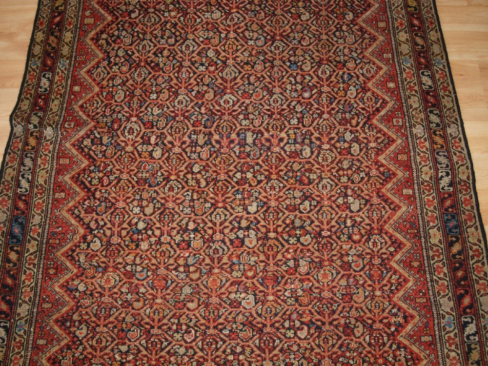 An antique hand-knotted Persian Malayer wool rug featuring an intricate red lattice pattern framed by multi-band decorative borders. View V