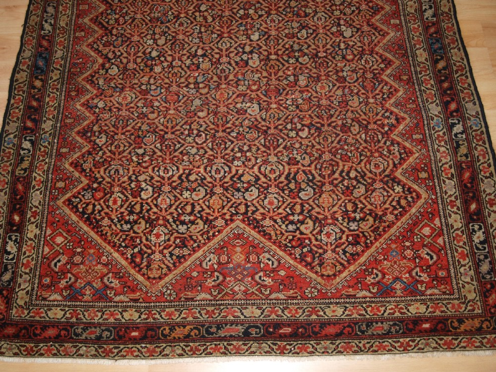 An antique hand-knotted Persian Malayer wool rug featuring an intricate red lattice pattern framed by multi-band decorative borders. View VI