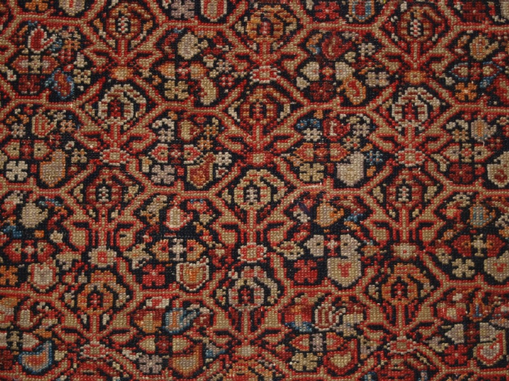 An antique hand-knotted Persian Malayer wool rug featuring an intricate red lattice pattern framed by multi-band decorative borders. View IX