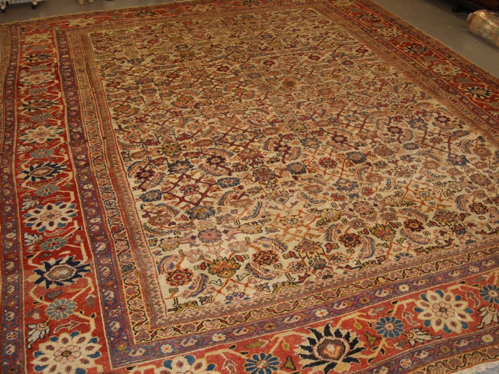 An antique Persian Mahal wool carpet featuring an all-over floral lattice pattern on an ivory ground, framed by a wide terracotta and navy border.