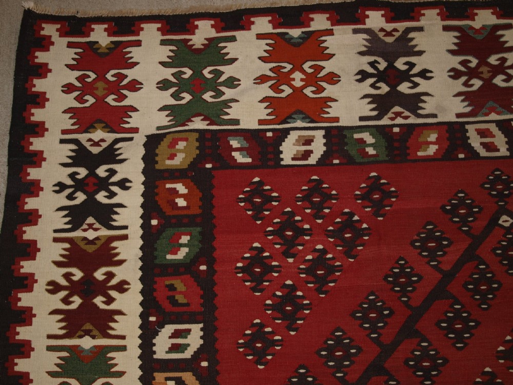 A large red wool Sharkoy flatweave kilim carpet featuring central geometric diamond patterns and a multi-coloured woven border. View II