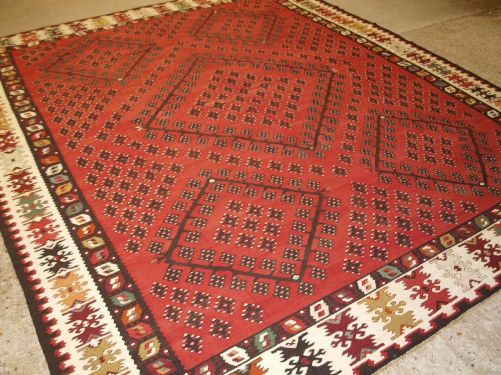 A large red wool Sharkoy flatweave kilim carpet featuring central geometric diamond patterns and a multi-coloured woven border. View III
