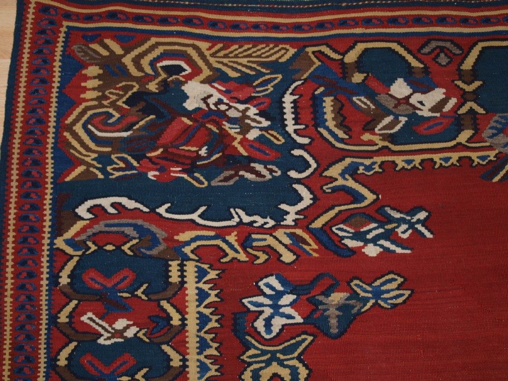An antique Persian Bijar flatweave kilim rug featuring a deep red central field with a central geometric medallion and floral motifs surrounded by decorative borders. View II