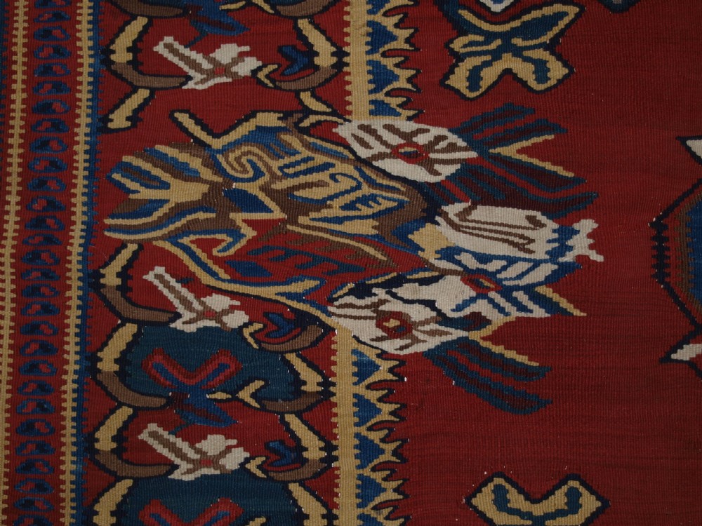 An antique Persian Bijar flatweave kilim rug featuring a deep red central field with a central geometric medallion and floral motifs surrounded by decorative borders. View VII