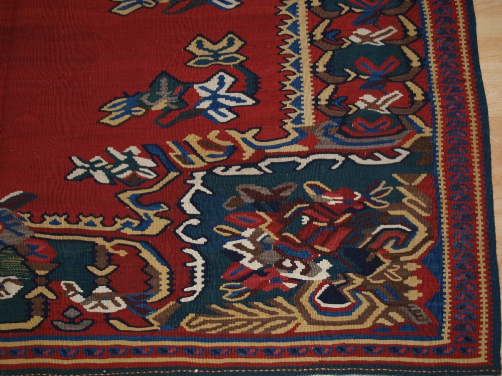 An antique Persian Bijar flatweave kilim rug featuring a deep red central field with a central geometric medallion and floral motifs surrounded by decorative borders. View IX